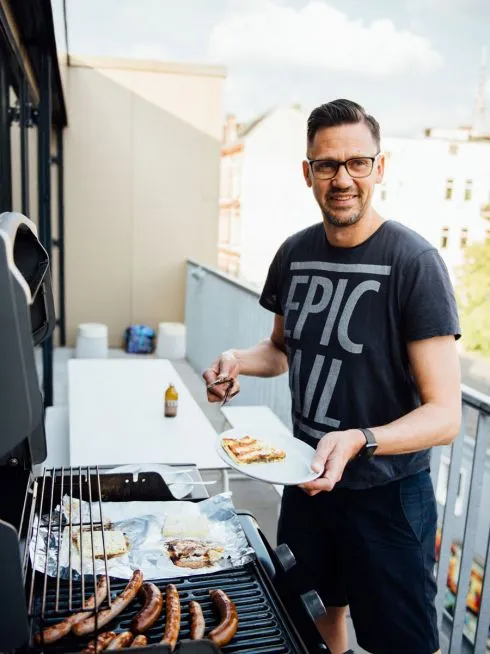 Bild eines Mitarbeiters beim Grillen auf dem Balkon
