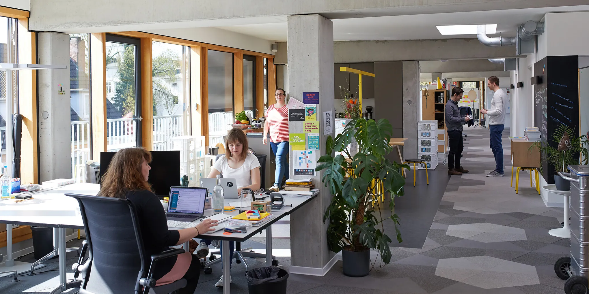 Bild des mindmatters Büros. Entwicklerinnen sitzen im Vordergrund am Arbeitsplatz