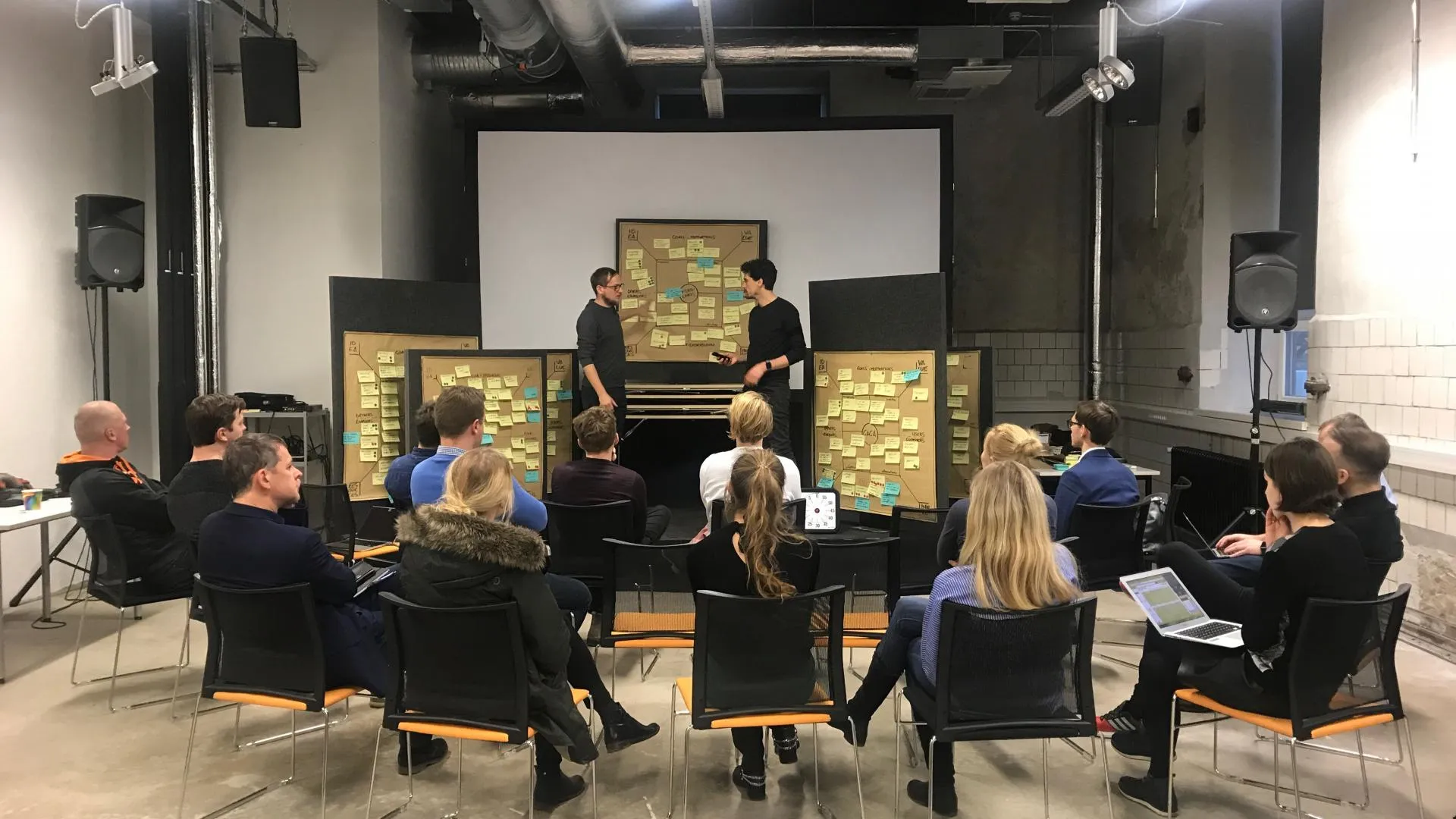 BIld eines Workshops mit Teilnehmern im Stuhl-Halbkreis versammelt