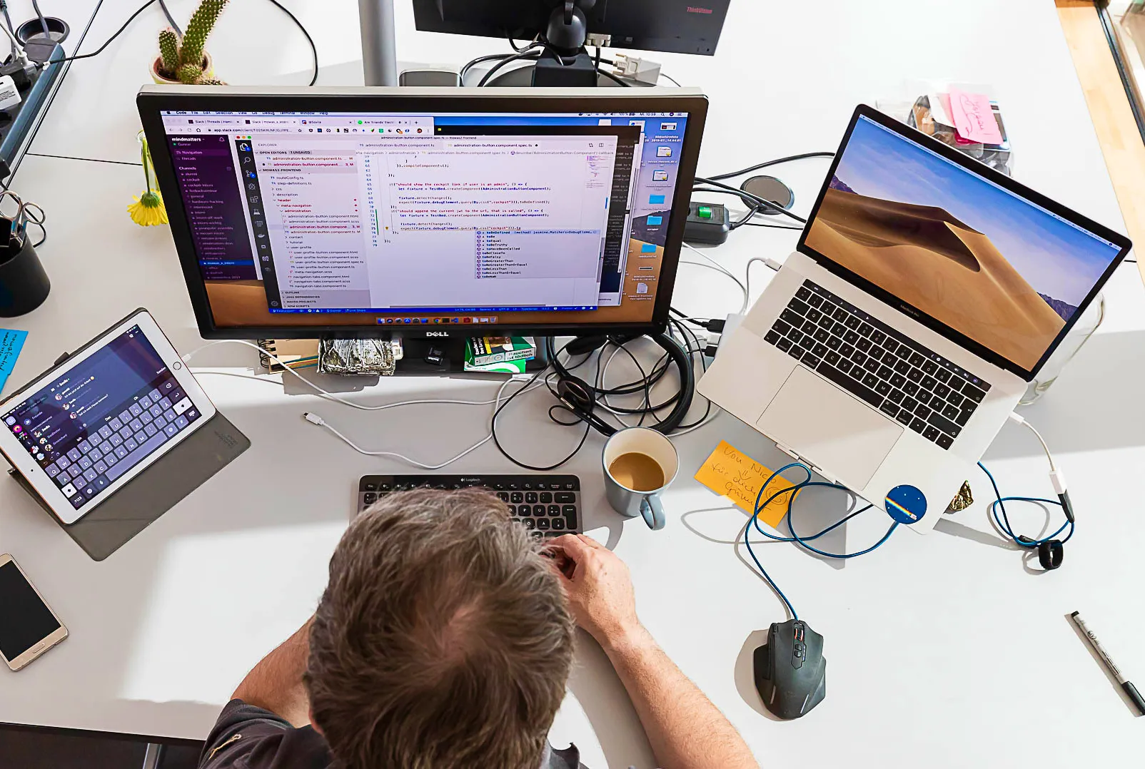 Softwareentwickler bei der Arbeit an individueller Softwarelösung mit drei Monitoren