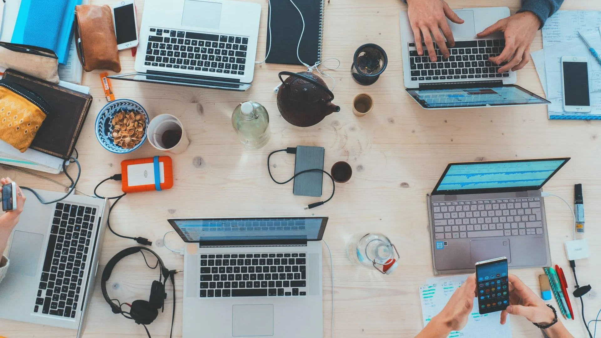 Ein Schreibtisch von oben mit vielen Computern, der eine typische Arbeitssituation im Team in der individuellen Softwareentwicklung darstellt.